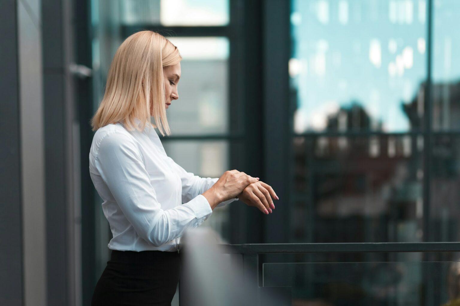 Beautiful business woman with white hair checks time on the watch