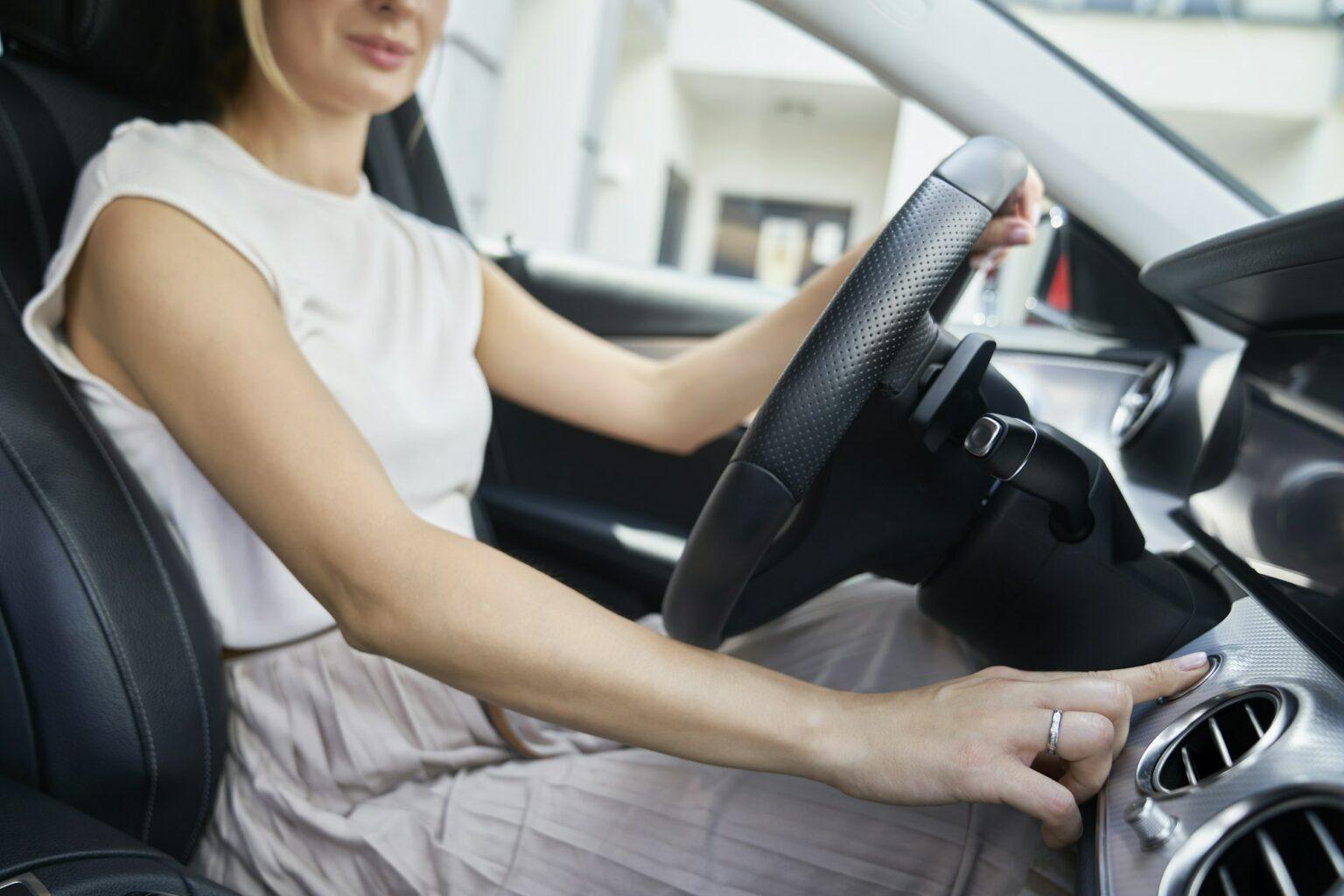 Close up of women's hand starts the car engine