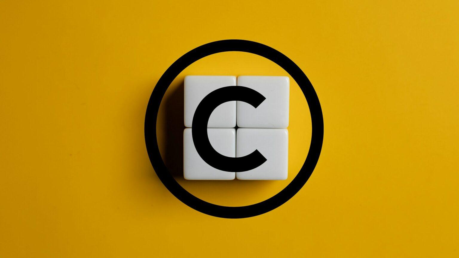 Copyright symbol on wooden blocks on yellow background. Concept of patenting or copyright protection