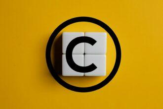 Copyright symbol on wooden blocks on yellow background. Concept of patenting or copyright protection