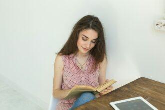 People, books and education concept - portrait of happy female student sitting with a book