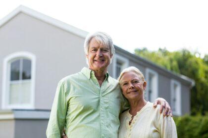 Senior couple standing in yard against house