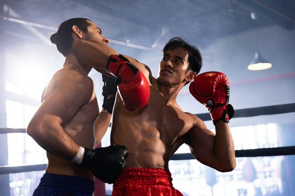 Sportsman muay thai boxer training fighting in gloves in boxing cage at the gym.