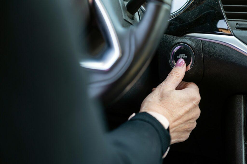 Woman hand pushing on car engine start-stop button. Modern car interior, closeup