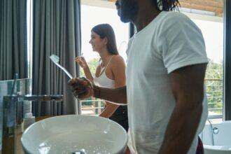 African American man and smiling Caucasian woman brushing teeth