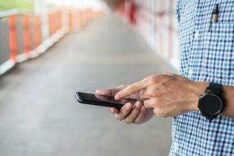 Businessman holding and using smartphone for sms messages