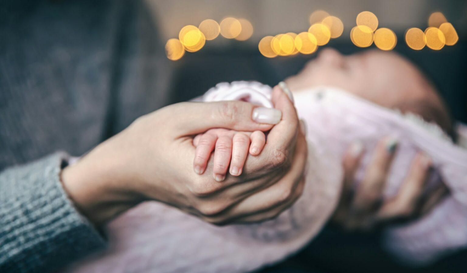 Close-up of a pen of a newborn baby girl in mom's hand.