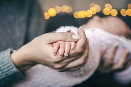 Close-up of a pen of a newborn baby girl in mom's hand.