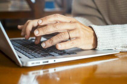 Close up of woman hands writing on keyboard laptop email or searching the net. People and online