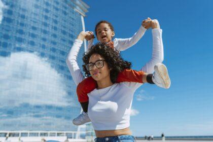 Cute daughter sits on mother's shoulders