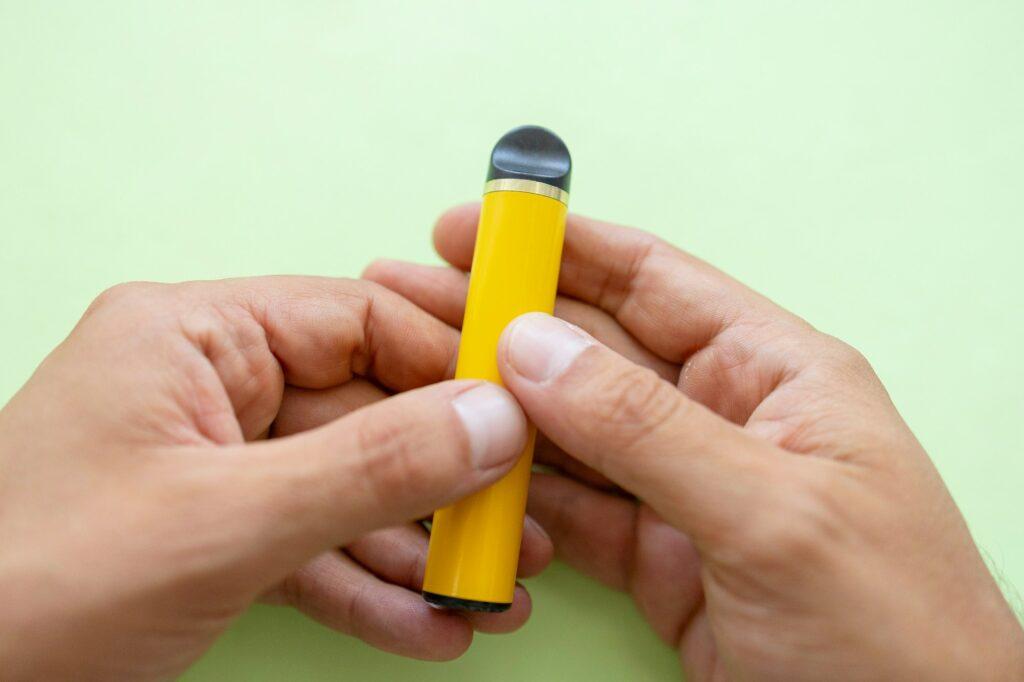 electronic cigarette in the hands of a man on a green background, the danger of electronic cigarette