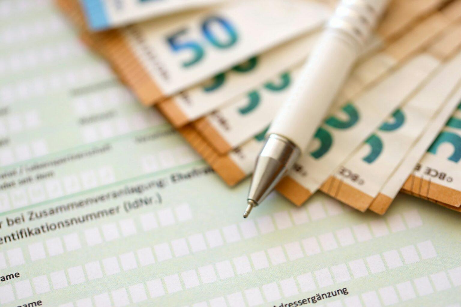 Filling german tax form process with pen and euro money bills close up. Tax paying period