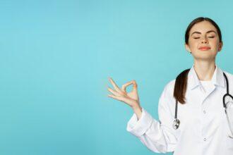 Mindfulness and meditation. Patient young woman doctor keep calm, hold hands in mudra, namaste