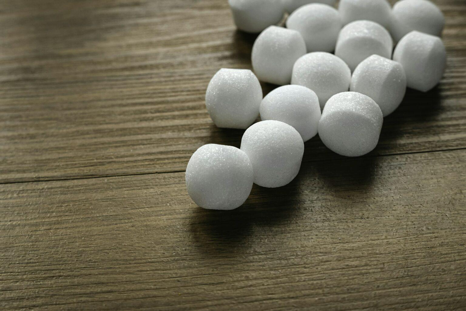 Naphthalene mothballs on wooden background.