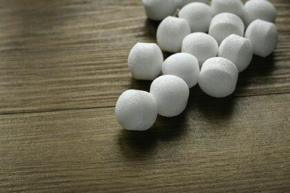 Naphthalene mothballs on wooden background.