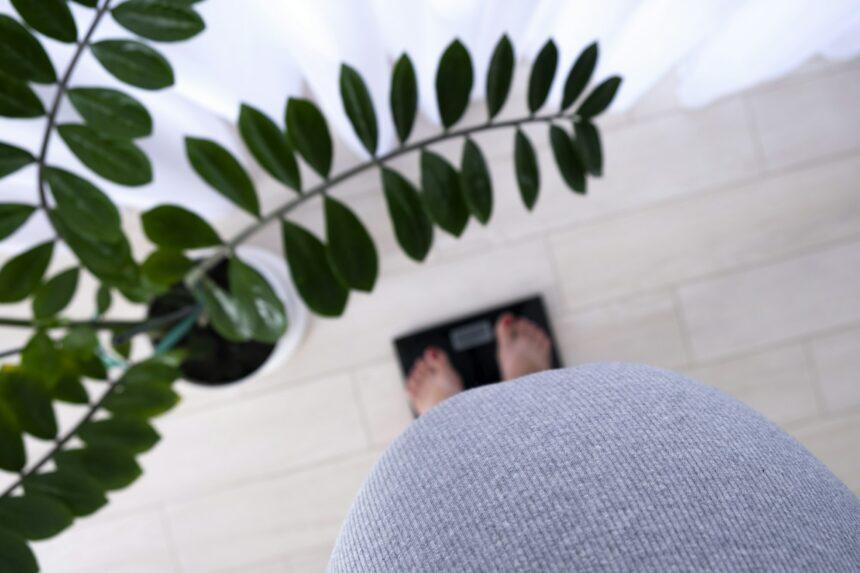 Pregnant woman on scales at home control her weight gain.