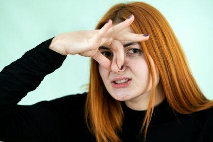 Funny pretty redhead girl showing bad smell sign with her fingers