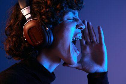 Male singer wearing headphones listening to music and singing with his mouth open, sound recording