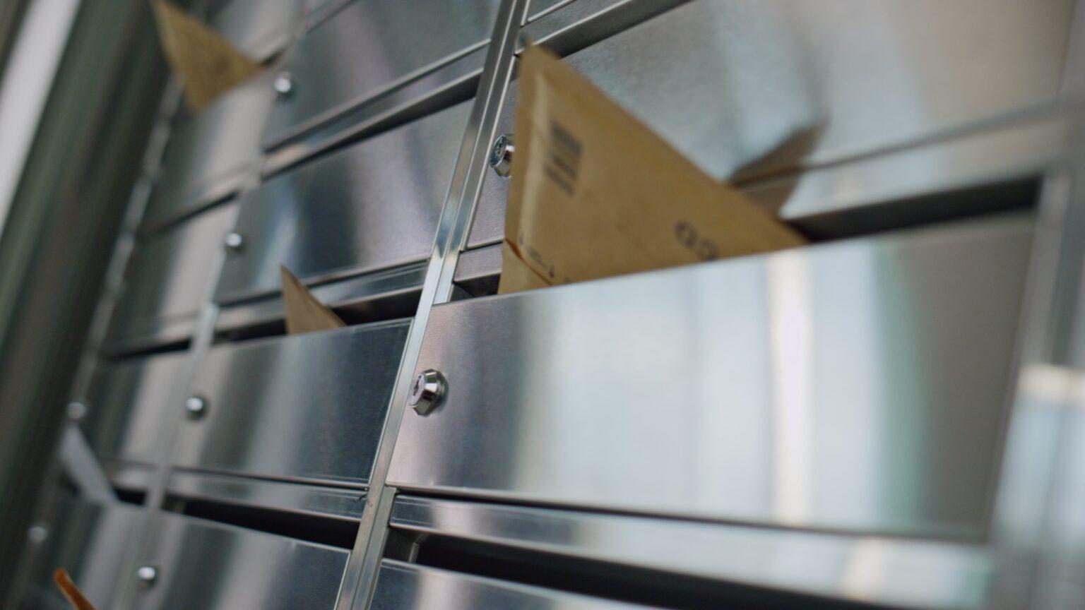 Paper envelopes stuck mailbox closeup. Silver post lockers in building corridor