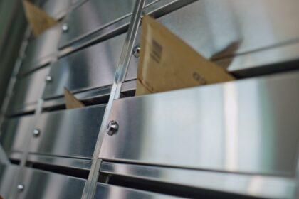 Paper envelopes stuck mailbox closeup. Silver post lockers in building corridor