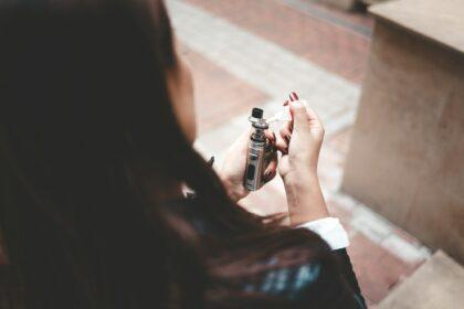 Woman refills liquid in e-cigarette closeup. Girl refills liquid in vape. Electronic cigarette