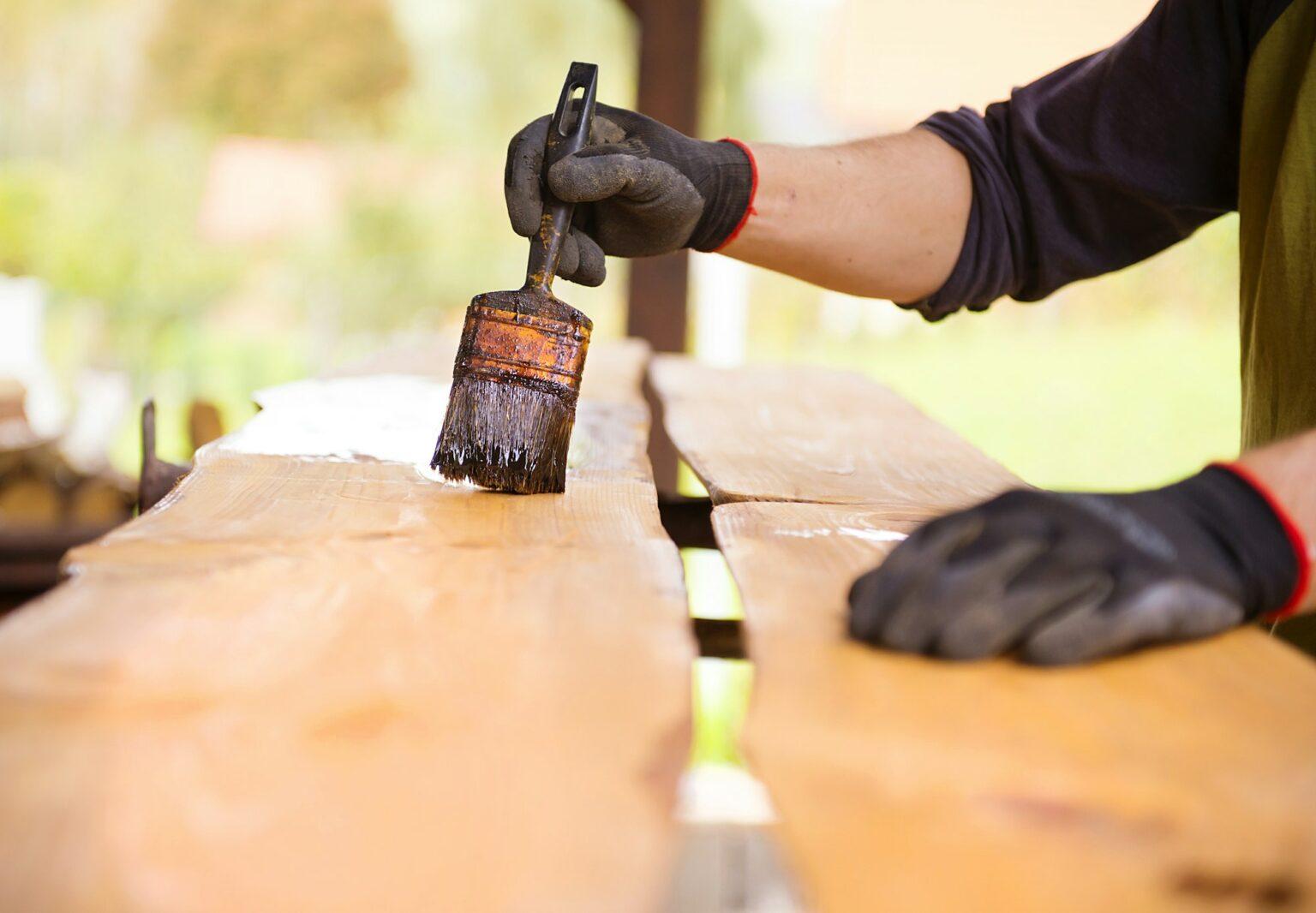 Workers hand varnishing wooden plank