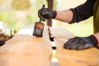 Workers hand varnishing wooden plank