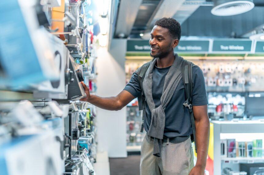 African man checking headphones in electronics store