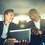 Business colleagues working online in the backseat of a car