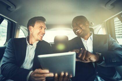 Business colleagues working online in the backseat of a car