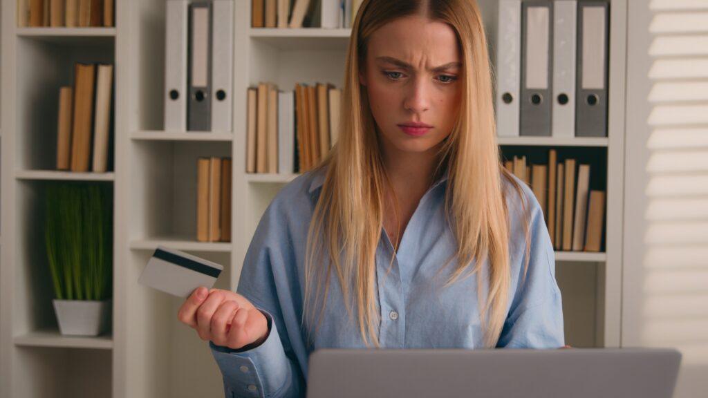 Confused puzzled client female hold bank credit card try to pay online annoyed with payment