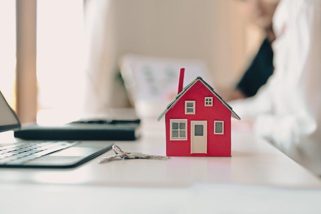 House model and keys on white table. Real estate investment and insurance concept.