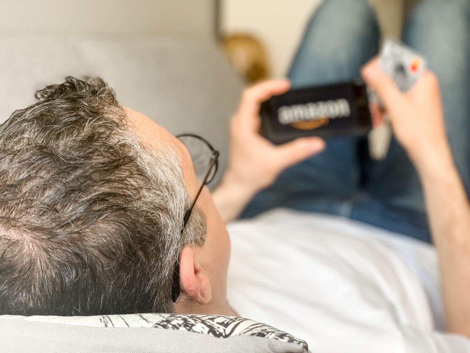 Middle aged adult man is doing shopping online at Amazon using mobile phone payment by credit card