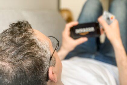 Middle aged adult man is doing shopping online at Amazon using mobile phone payment by credit card