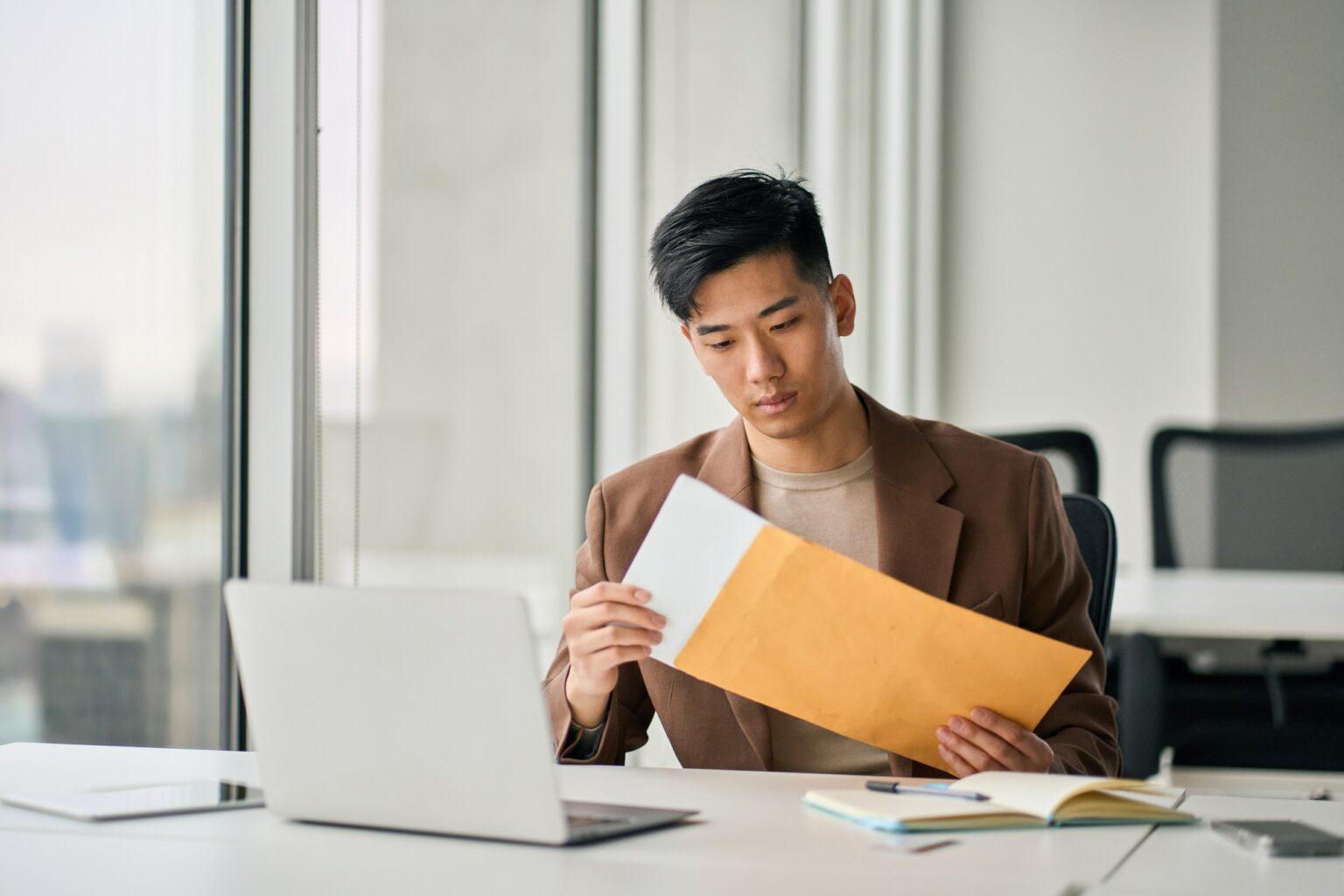 Young Asian professional business man receiving business mail letter in office.