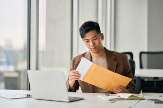 Young Asian professional business man receiving business mail letter in office.