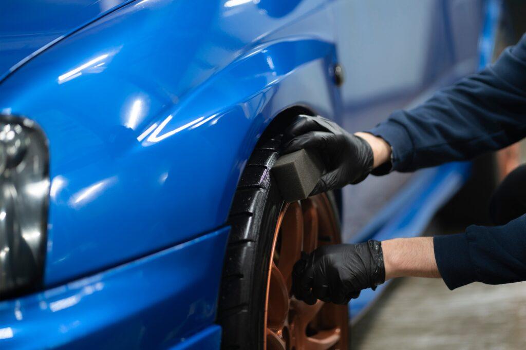 applying a black car tire polish on the wheels