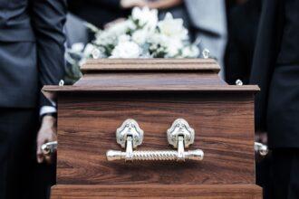 Coffin, people and funeral with death, grief and service with family carry casket to grave outdoor.