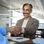 Happy mature business man manager and recruit handshake at job interview.