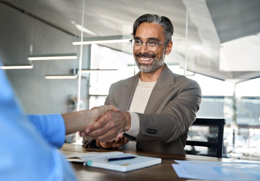 Happy mature business man manager and recruit handshake at job interview.