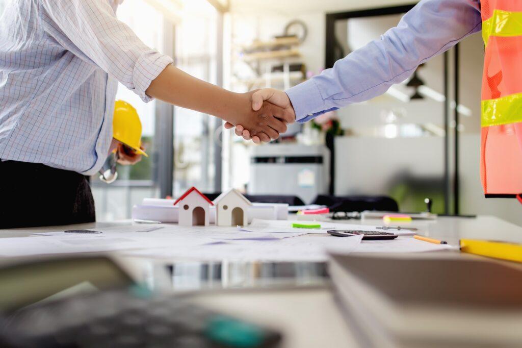 Investor and engineer shaking hands at meeting.