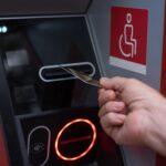 Woman hand inserting ATM credit card into bank machine to transfer money or withdraw