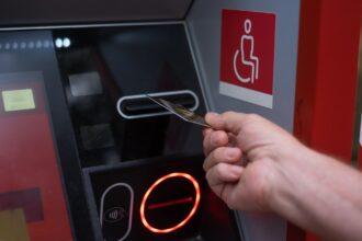 Woman hand inserting ATM credit card into bank machine to transfer money or withdraw