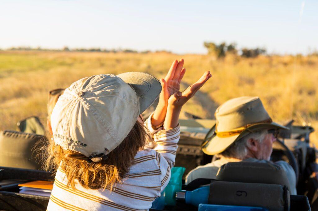 Young boy in safari vehicle at sunrise, Okavango Delta, Botswana.