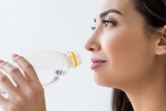 asian woman drinking water from bottle, isolated on white