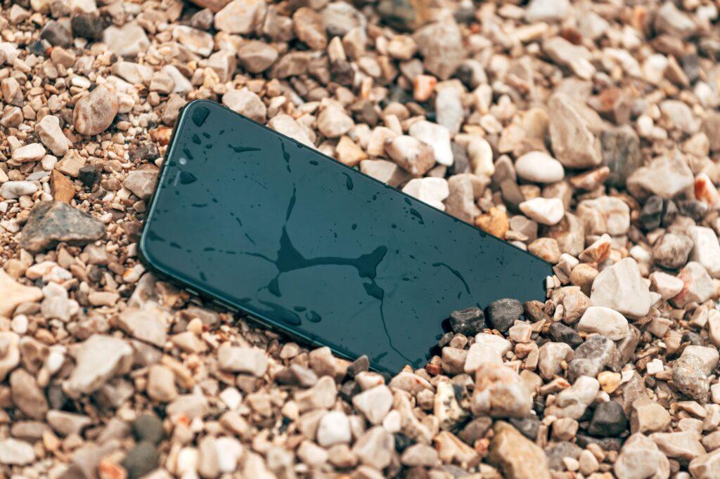 Wet and damaged smartphone in beach pebbles