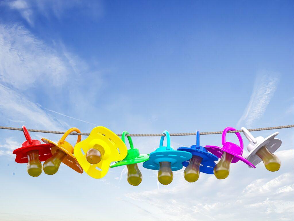 Row of child pacifier, soother and baby dummies on rope.