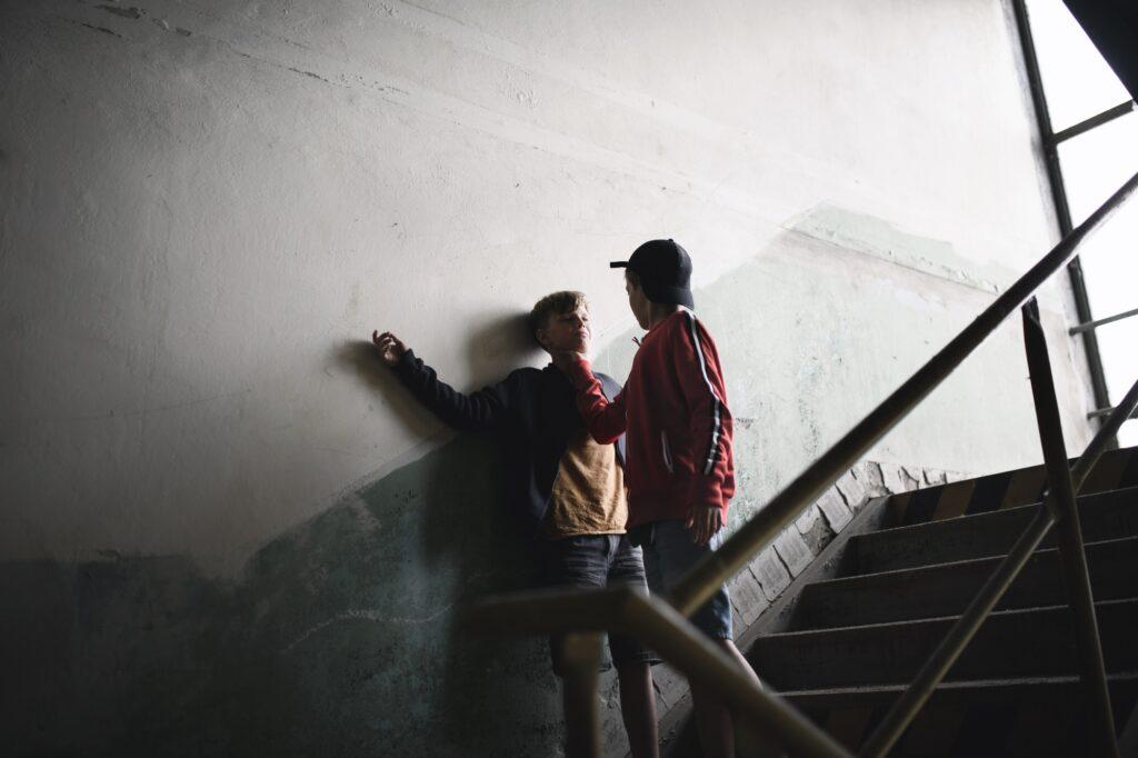 Teenage boy attacked by thug in abandoned building, gang violence and bullying concept.