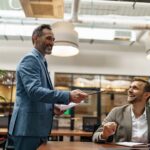 Mature business coach or speaker make flip chart presentation to diverse businesspeople at meeting