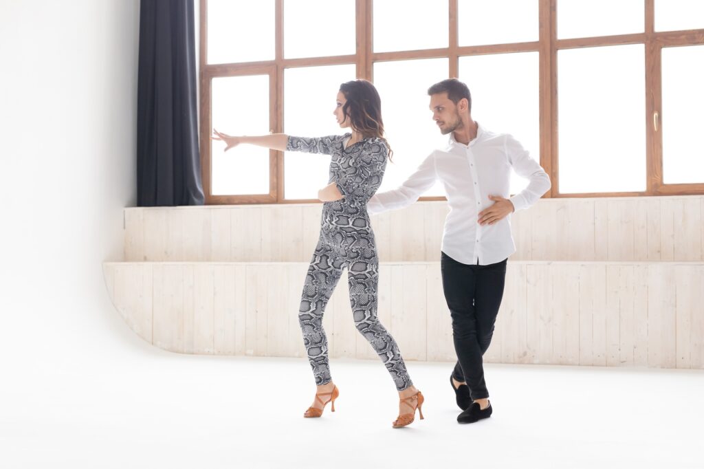 Young love couple dancing social danse kizomba or bachata in dance class with big window